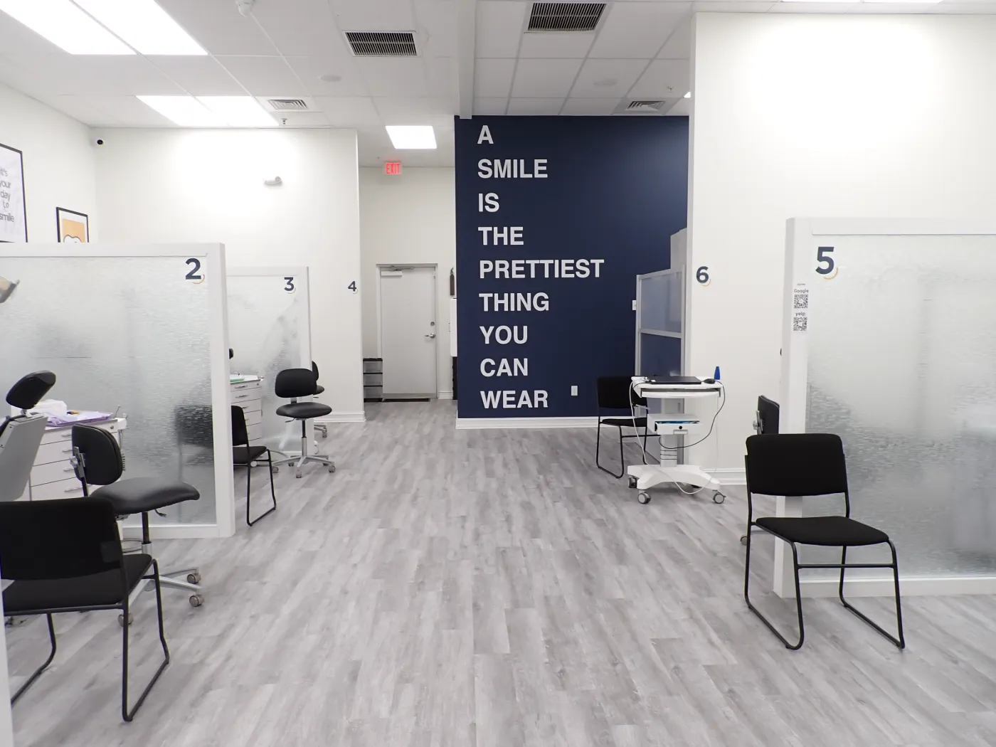 Open treatment bay with the 'A smile is the prettiest thing you can wear' wall